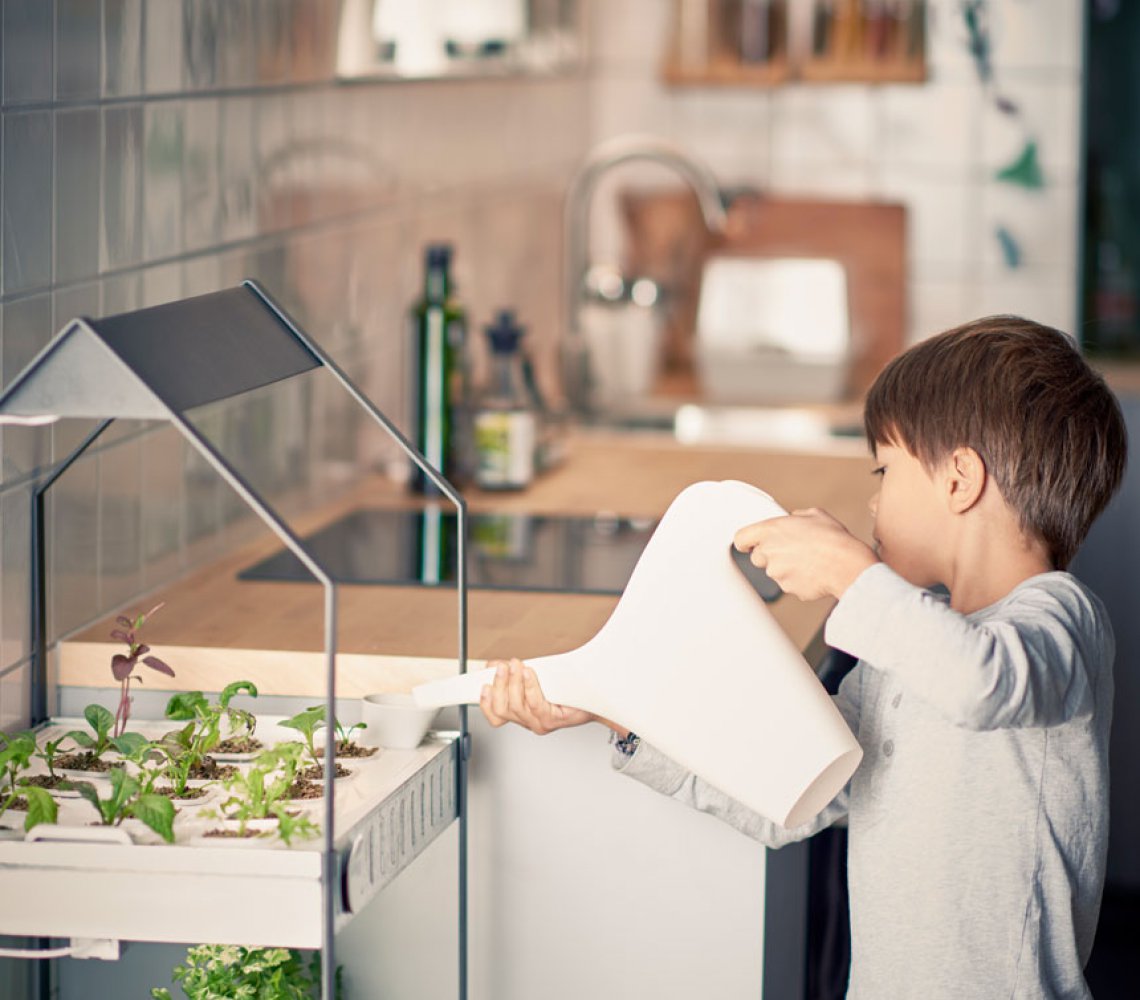 Kid watering plants in the IKEA Växer plant stand
