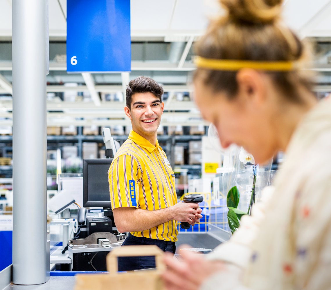 Cashier helping customer by the cash register in the IKEA store.