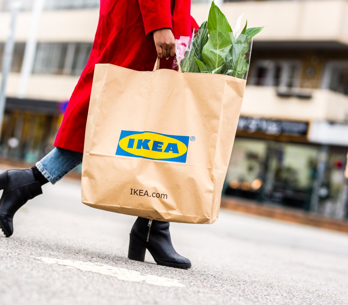 Woman walking in the streets with an IKEA bag with a peace lily.