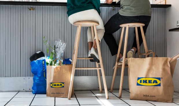 Friends sitting at a cafe with several bags from the IKEA store.