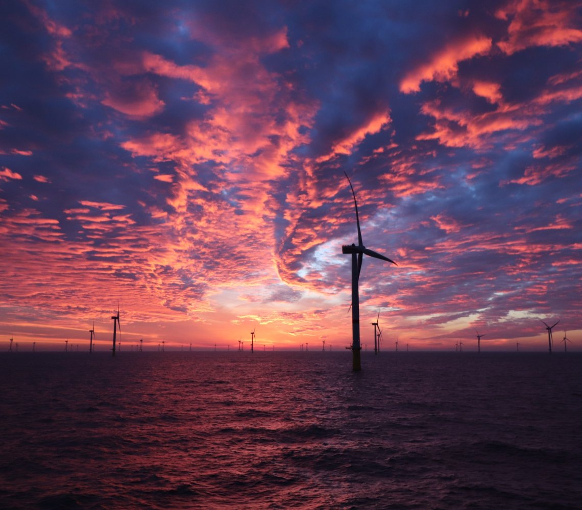 Sunset over wind turbines in the ocean